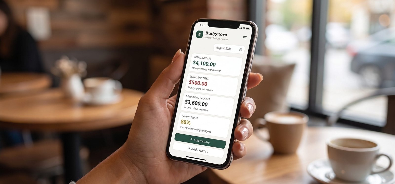 Budgetora mobile budget tracker app held in hand showing monthly balance and savings rate.